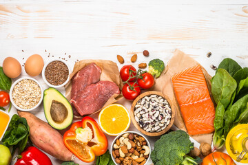 Healthy food products at white. Balanced nutrition. Salmon fish, beef, beans, nuts and vegetables. Top view image with copy space.