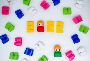 Fototapeta na wymiar Retro colorful building blocks, toys plastic figures: girl in 2022 numbers and green boy on white background