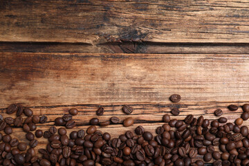 Many roasted coffee beans on wooden table, flat lay. Space for text