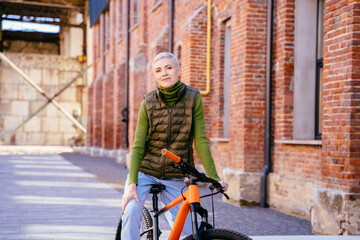 Portrait of friendly trendy woman in casual clothes walking on a city bike outdoor. Active age, leisure and lifestyle concept. Active female outside having fun in autumn season.