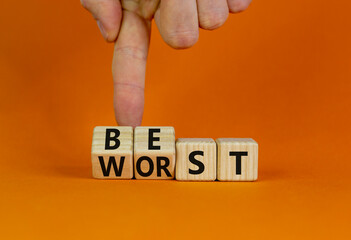Best or worst symbol. Businessman turns wooden cubes and changes the word best to worst. Beautiful orange table, orange background, copy space. Business and best or worst concept.