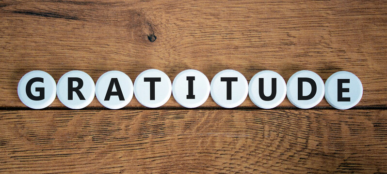 Gratitude symbol. The concept word Gratitude on white circles. Beautiful wooden table, wooden background. Business and gratitude concept. Copy space.