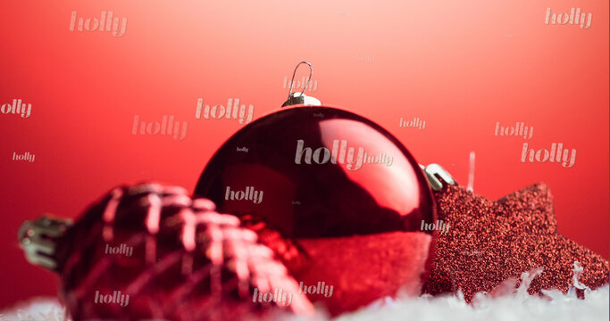 Image of holly text in repetition over christmas decorations