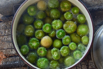 Tomate verde dentro de una cacerola con agua hirviendo. 