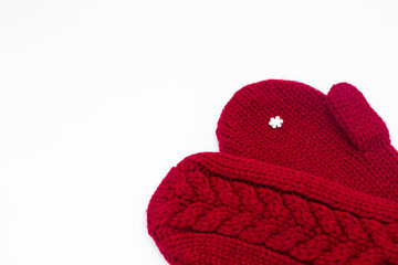 A knitted red mittens with one white snowflake on a white background, isolated. Concept of Christmas, winter, love. Care and Valentines day. Copy space