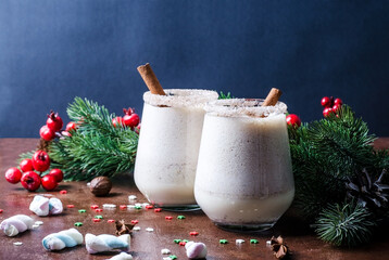 Egg punch, egg liqueur in glasses with Christmas decor. Eggnog Christmas drink in wine glasses on a...