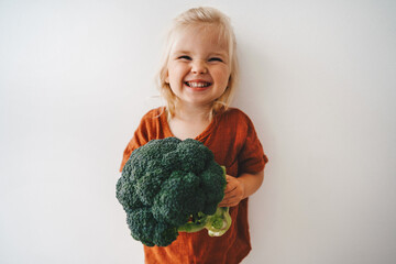 Child with broccoli vegetable healthy food vegan cooking eating sustainable lifestyle organic veggies harvest plant based diet nutrition funny kid girl happy smiling toddler - 470727365