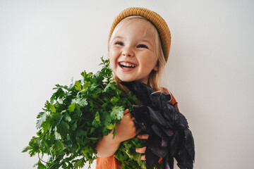 Child girl with coriander and basil bunch healthy vegan food organic harvest gardening plant based diet nutrition funny kid happy smiling