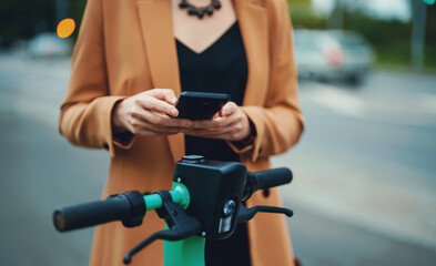Woman using app on smartphone to unlock electric scooter on the street.