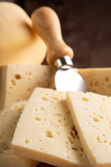 Semi-cured cheese from Brazil, beautiful Brazilian cheeses and cutting accessories arranged on light rustic wood, selective focus.