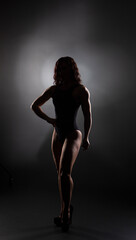 Athletic body of young woman over dark background. Fitness concept.