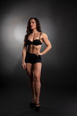 Athletic body of young woman over dark background. Fitness concept.