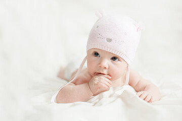 newborn baby girl in pink knitted hat on a bed