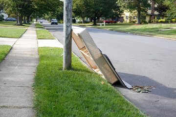 Used box spring mattress leaning against a utility pole left on the side of a street waiting for...