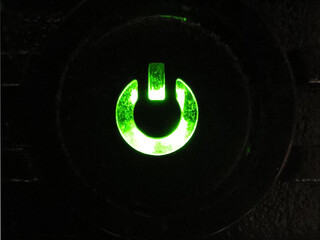 Ein grün leuchtendes Symbol auf einem Schalter als Startknopf
