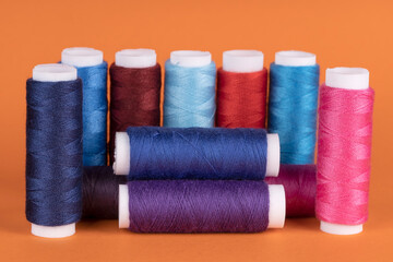 Bobbins of sewing thread of different colors isolated on orange