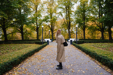 Girl walks in the autumn park. Beautiful autumn landscape, fall foliage. Outdoor activities. Autumn walk in the garden. Enjoy the weather and fresh air. Travel and exploration