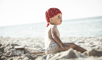 Toddler on vacation. Millennial child is playing on the beach. Travel in wanderlust style.