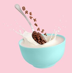 Cocoa cereal letters falling into blue bowl with splashing milk. Breakfast for children. Isolated...