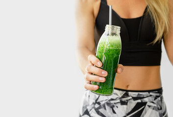 Healthy lifestyle concept. Fitness woman holding a bottle of broccoli and spinach smoothie. Copy...
