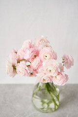 The background of ranunculus colors is gently pink. A riotous peony-shaped rose bouquet