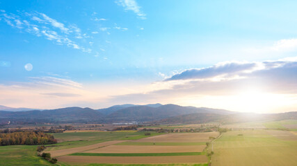 Beautiful summer landscape, green fields, trees and the setting sun against the blue sky. Poland, Klodzko