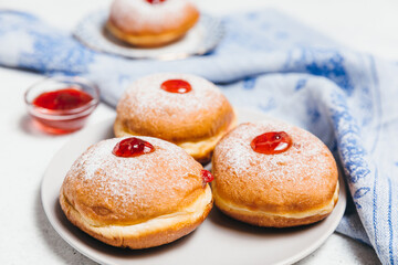 Sufganiyot jelly doughnuts cooked in oil on white table background. Traditional Jewish festive food dessert for Hanukkah holiday. Flat lay, top view.