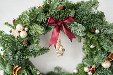 Fototapeta na wymiar Beautiful festive wreath of fresh spruce on Gray wall. Xmas circlet with ornaments and balls. Christmas mood.