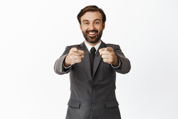 Its you. Enthusiastic corporate man, office manager pointing at camera and smiling, recruiting for job, inviting people join company, naming winner, white background