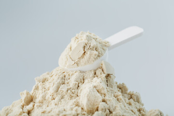 Whey protein isolate with a measuring spoon on a white background.