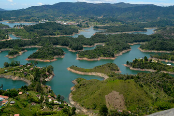 Naklejka na ściany i meble View to the Islets of the El Peñol Reservoir in Guatapé, Antioquia. Houses between river and mountains of Colombia on a sunny day. Tourist destination. 