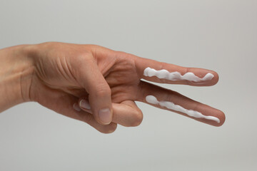 A person applying the correct amount of sunscreen for face and neck.