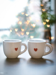Obraz na płótnie Canvas Couple valentines coffee mug with red color mini heart. Cozy atmosphere with lighting heart bokeh in background with copy space, romantic couple and happy valentine concept