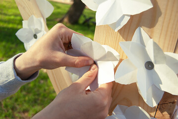 Children's crafts made of paper and wood by the hands of a child in nature. A paper flower in the hands of a boy.