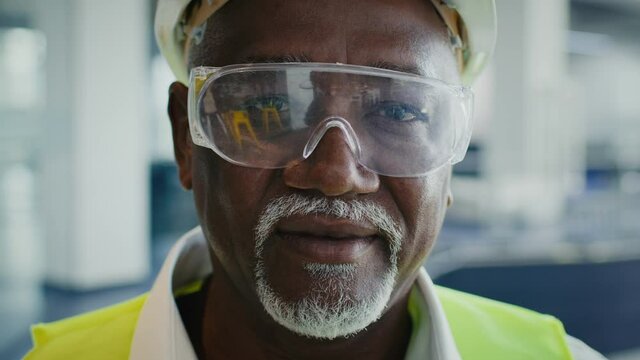 Closeup Of Mature Black Construction Worker In Protective Helmet, Vest And Eyeglasses