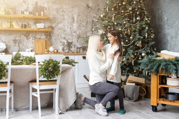 Mother and daughter in front of Christmas tree.
