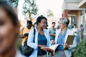 African American university student talking to her teacher at campus.