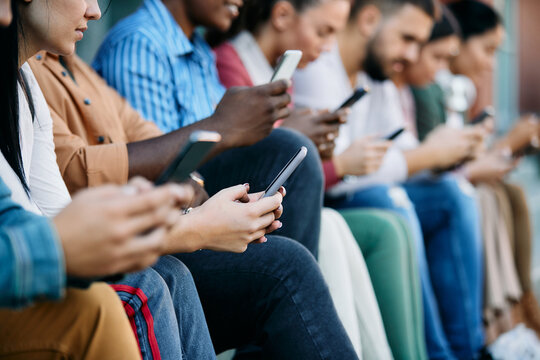 Close-up of woman and her college friends using their smart phones outdoors.