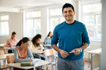 Portrait of happy high school teacher in the classroom looking at camera. - obrazy, fototapety, plakaty