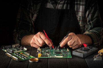 Computer or electronics repair. Master tester checks the electronic board in the service workshop.