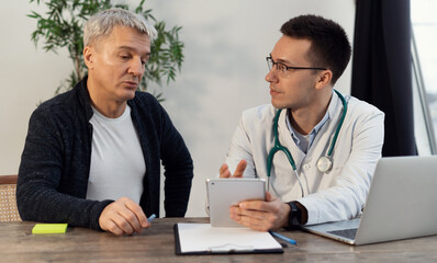 Consultation visit to a medical office. Male client at the clinic. The doctor communicates with patients in his office.