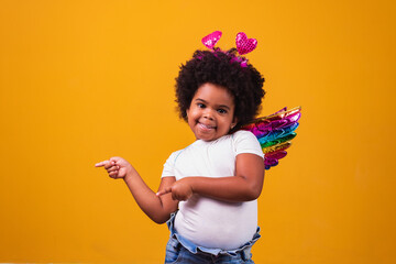 adorable afro girl dressed in colorful outfit on yellow background. Children's Day. afro girl with...