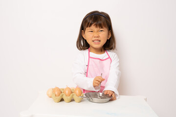 Beautiful little asian girl cooking isolate on white background