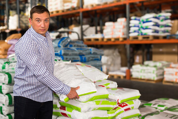 Ordinary man buying compost soil for gardening in hypermarket