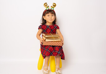 Cute smiling little asian girl in santa hat sitting with gift box isolated over white background.