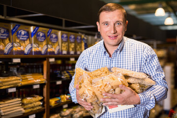 Cheerful positive male customer choosing pasta in supermarket