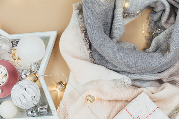 Women fashion winter clothes and accessories. Female look with knitted white and pink scarf,  garlands on beige pastel background. New year and Christmas celebration mockup 