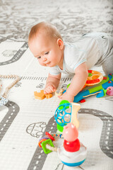 Baby plays on floor with educational toys, rattles and teething toys. Crawling babies at 8 months..