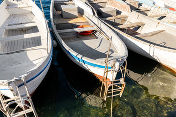 Row of many small old wooden vintage colorful bright fishing ships moored at fisherman village marina clear water bay on bright sunny day. Sea harbor with traditional retro vessels background