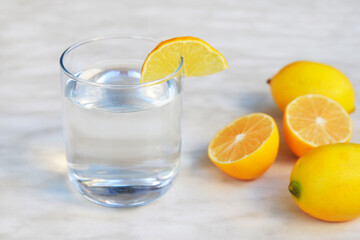  A glass of lemon juice and lemons around on a table.